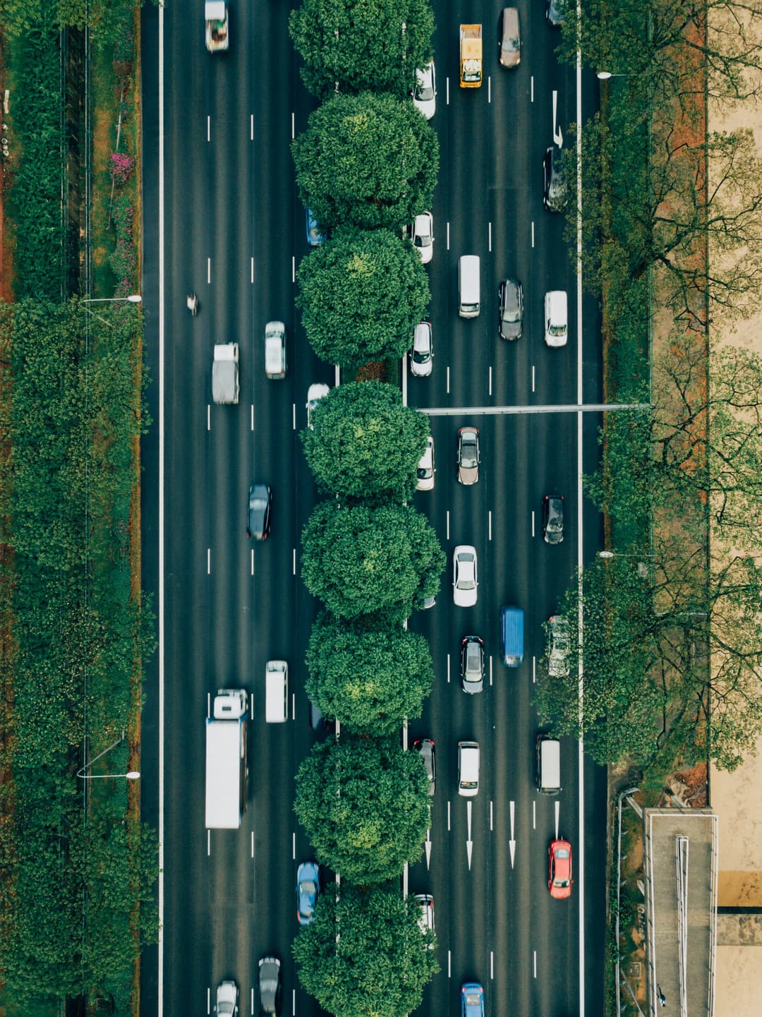 Luftaufnahme einer mehrspurigen Stadtautobahn mit dichtem Verkehr und begrüntem Mittelstreifen